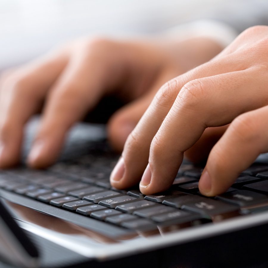 Close-up of male fingers typing a business document on the black laptop